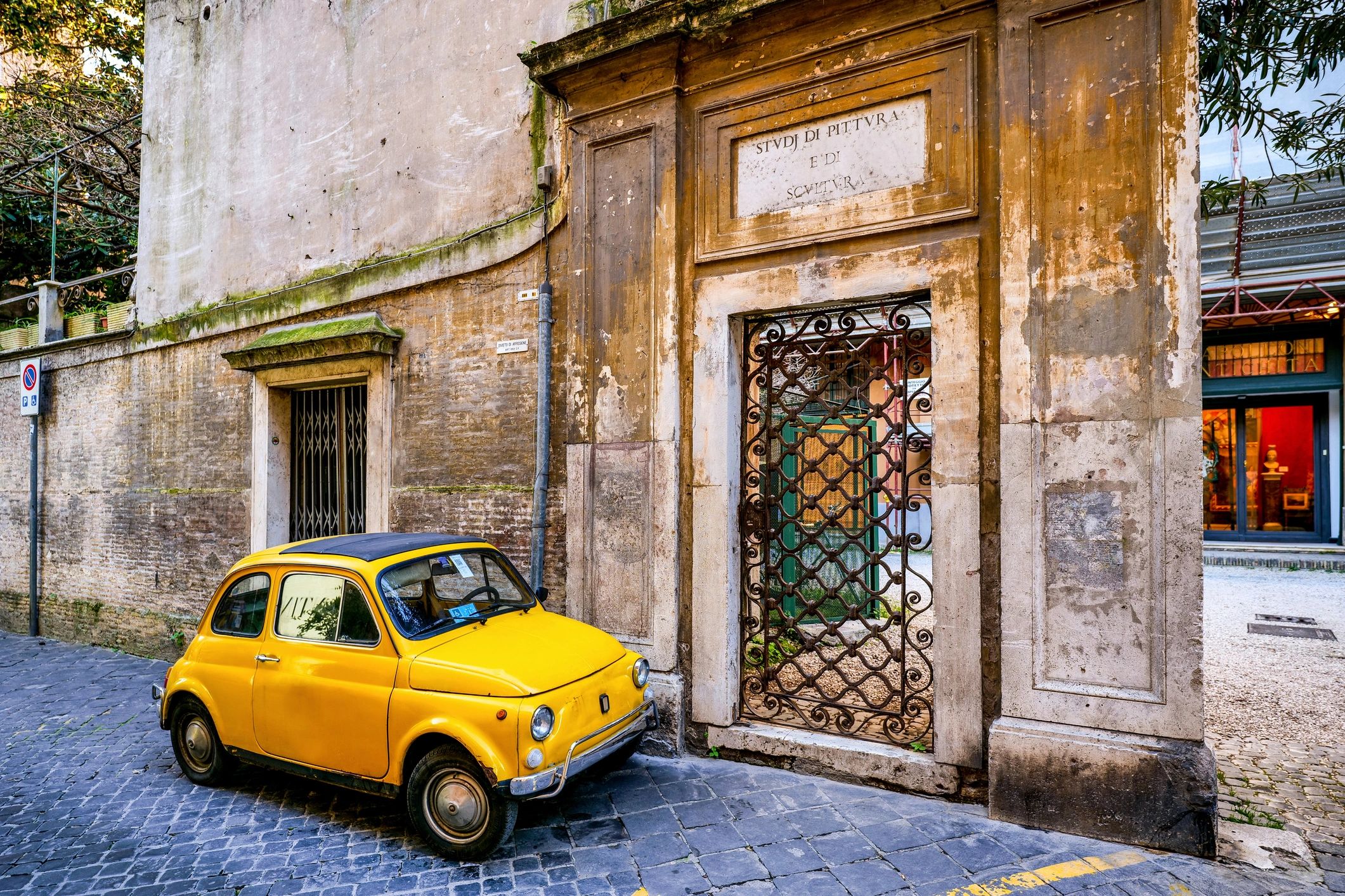 Vintage yellow compact car parked on a historic street